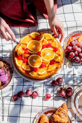 Female cut pie with oranges for a event day on picnic checked cloth