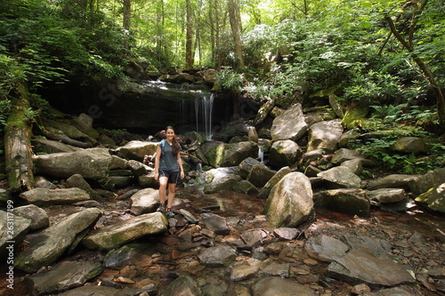 Young woman explores a small trailside waterfall in the Great Smoky Mountains National Park, Tennessee, in early summer.