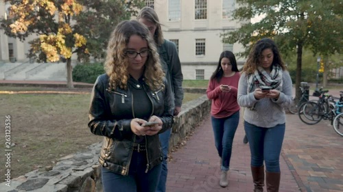Group of students all on their mobile phones walking and ignoring each others