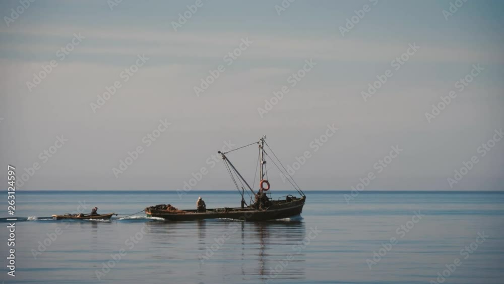 Silhouette of a towing boat pulling a small fishing boat to the sea. Silhouette of a towing boat pulling a small fishing boat to the sea.