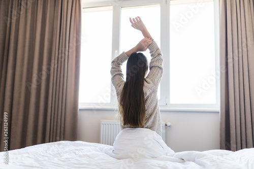 Rear view of woman stretching in bed after wake up in morning
