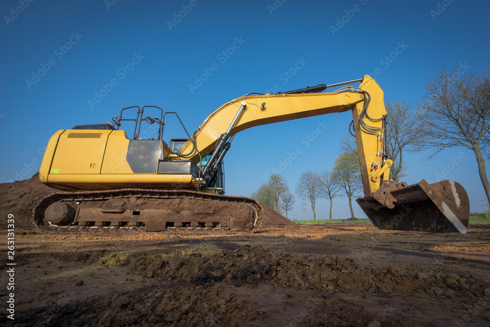 Gelber Bagger trägt das Erdreich auf einer Baustelle ab Gelber Bagger trägt das Erdreich auf einer Baustelle ab