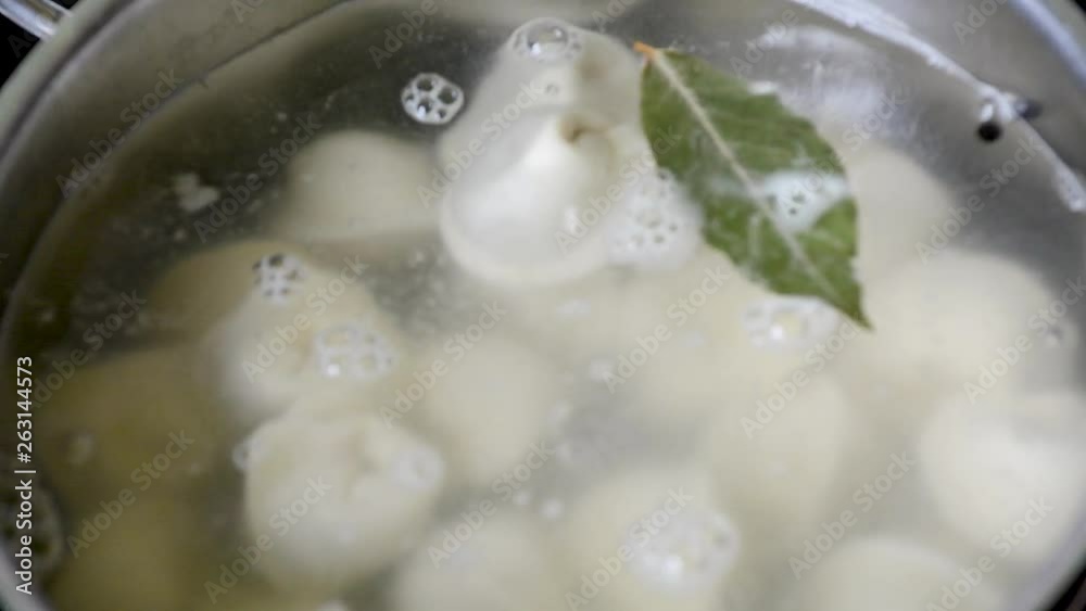 A man cooks ravioli or dumplings in boiling water, throwing them in turn into boiling water A man cooks ravioli or dumplings in boiling water, throwing them in turn into boiling water
