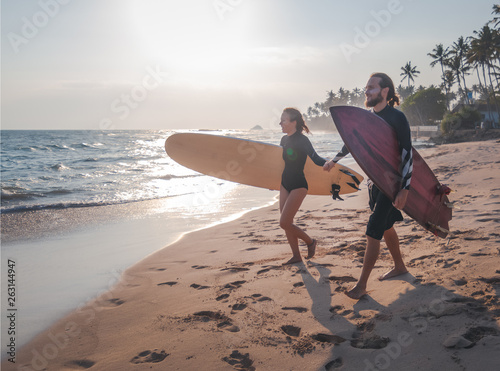 Canvas Print Young beautiful couple of friends on the ocean with surfboards in their hands, s