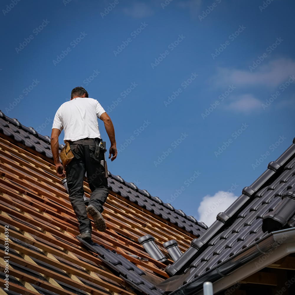 Dachdecker läuft auf einen fast fertig eingedecktes neues Dach Dachdecker läuft auf einen fast fertig eingedecktes neues Dach