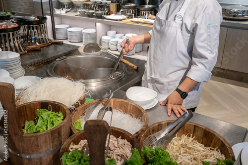 Chef preparing noodle with strainer over Thai chamber pot