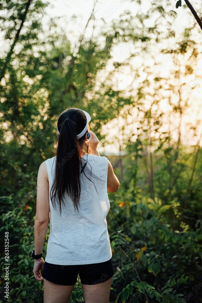Young woman runner wears white sport vest, white cap, black short pants drinks mineral water after running. Young woman runner wears white sport vest, white cap, black short pants drinks mineral water after running.
