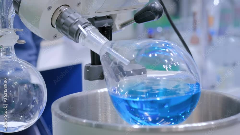 Laboratory rotary evaporator - homogenization process - rotating chemical flask for evaporate solvent from blue liquid at pharmacy factory or medical exhibition. Pharma, chemistry and science concept