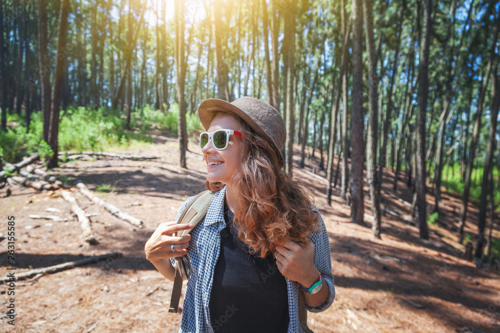Young beautiful girl enjoying a walk in the pine forest, camping in the sun
