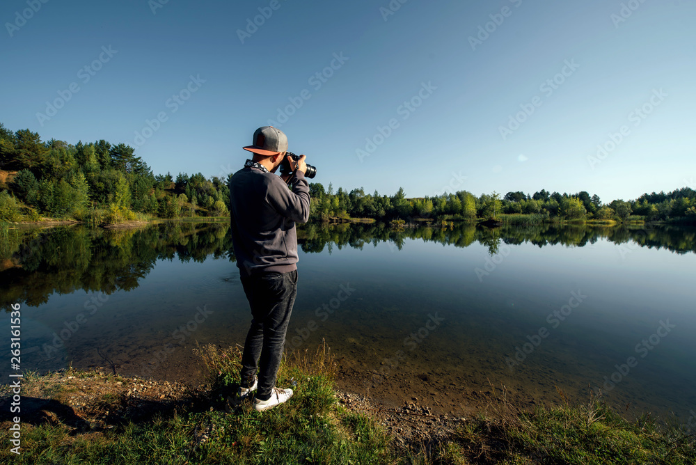 Obraz premium Young man taking pictures of a lake