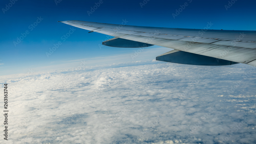 Obraz premium Close up of window with airplane wing. Beautiful cloudscape with clear blue sky.