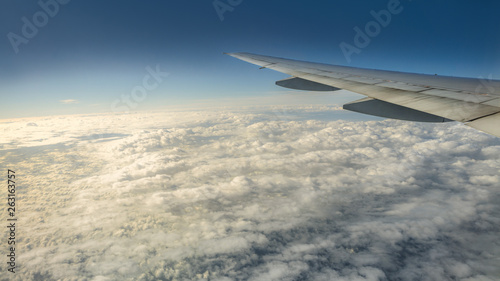 Close up of window with airplane wing. Beautiful cloudscape with clear blue sky.