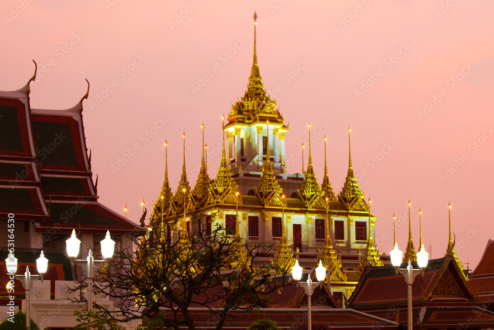 Naklejka premium View of the top of the old Chedi Loha Prasat in lilac twilight. Bangkok, Thailand