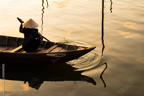 Vietnamese woman in traditional bamboo hat rowing