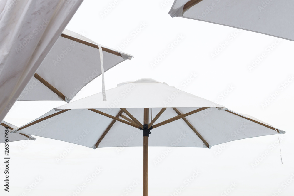 Summer day at the beach with white umbrellas.