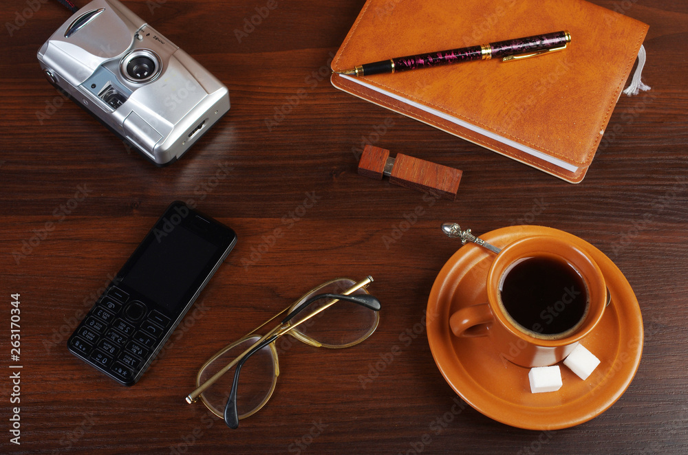 A cup of coffee, a mobile phone, a camera, a notebook, a pen A cup of coffee, a mobile phone, a camera, a notebook, a pen
