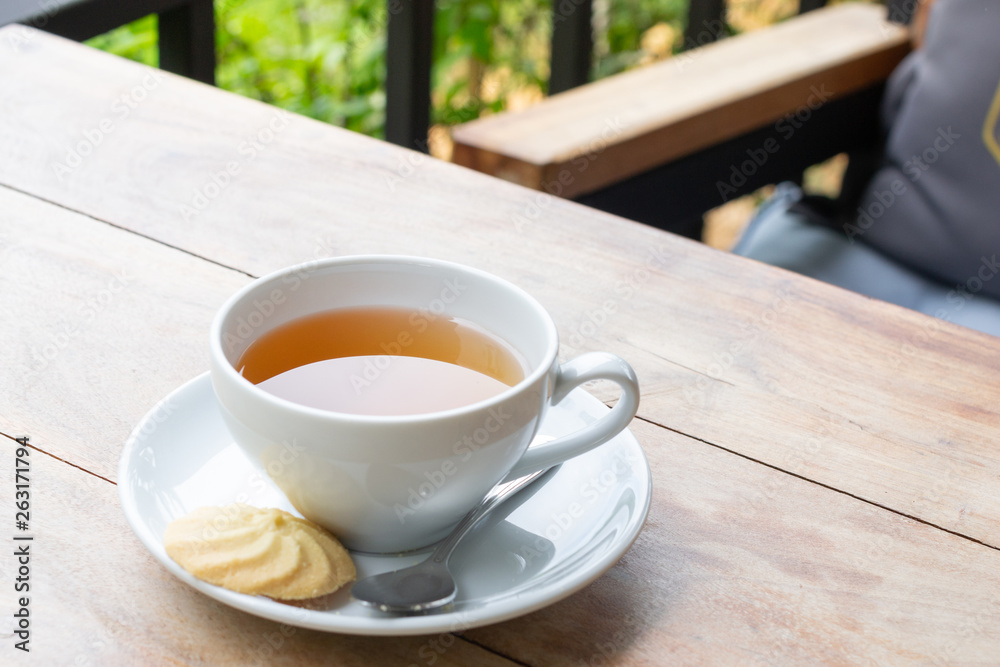 Hot tea in teacup with cookie on saucer on wooden table. Hot tea in teacup with cookie on saucer on wooden table.