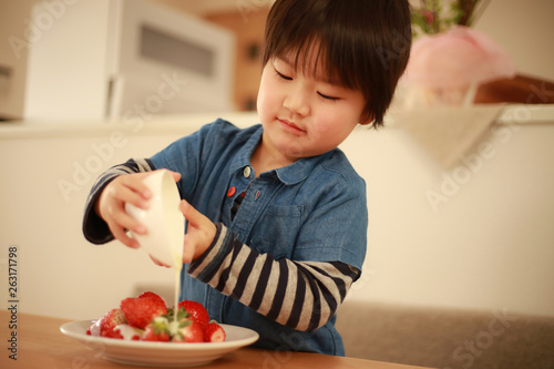 イチゴに練乳をかける男の子