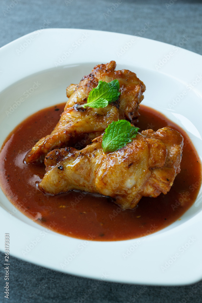 Spicy drumstick or Fried chicken with tomato sauce and black pepper in white dish on concrete table.