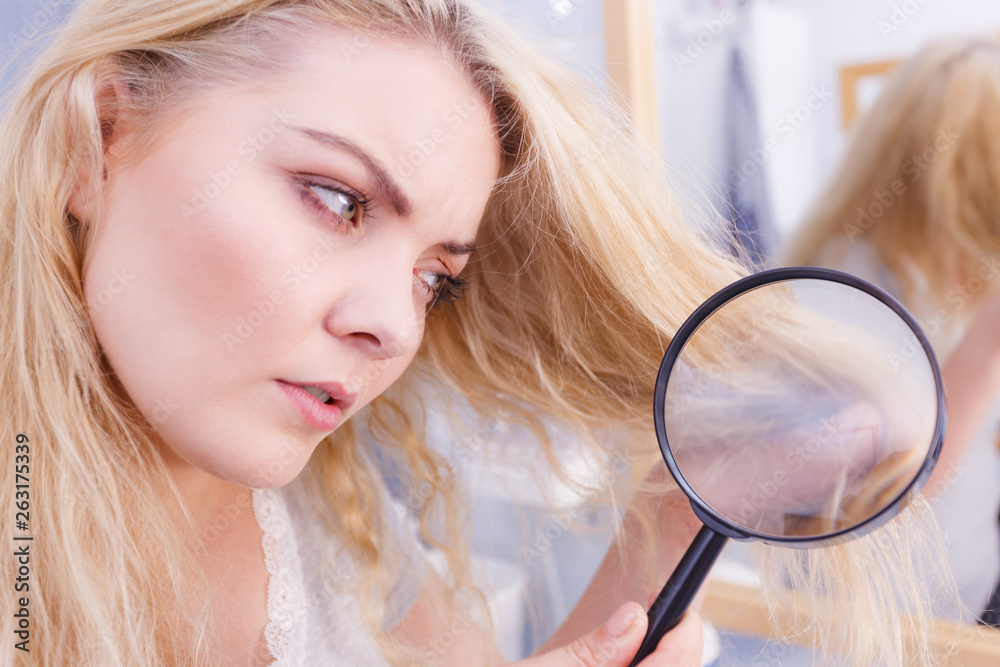 Woman looking at hair ends through magnifying glass Woman looking at hair ends through magnifying glass