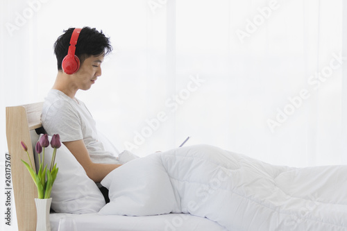 Asian man wearing red headphone, listening music.