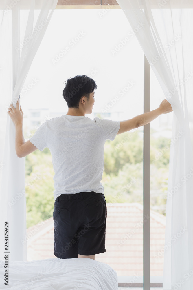 Man open the curtain and look outside the window.. Man open the curtain and look outside the window..