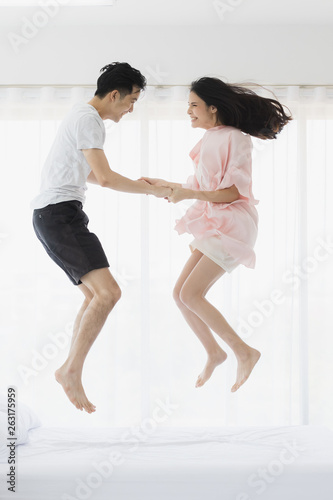 Lovely Asian couple jumping on bed in bedroom.. © Bangkok Click Studio
