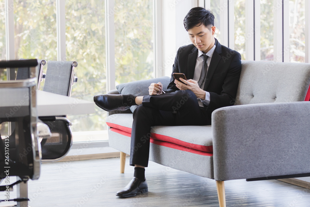 Asian businessman using cellphone in office.. Asian businessman using cellphone in office..