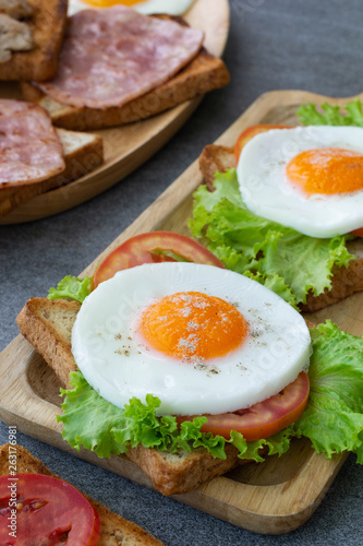 Homemade sandwich or toast wheat bread with fried egg,lettuce,tomato in wooden table on the concrete table.
