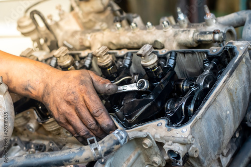 Closeup man's hand is repairing a engine with equipment to work. man use the wrench to tighten the cylinder.