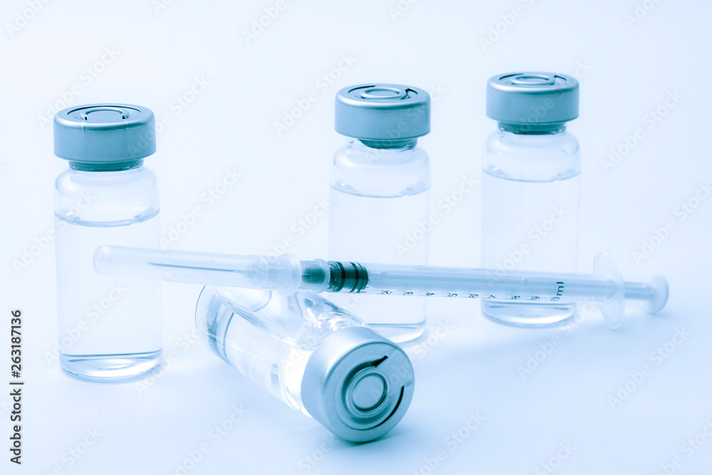 Vaccines, botulinum toxin and insulin ampules concept theme with glass vials with clear liquid next to a syringe and a hypodermic needle isolated on white background Vaccines, botulinum toxin and insulin ampules concept theme with glass vials with clear liquid next to a syringe and a hypodermic needle isolated on white background