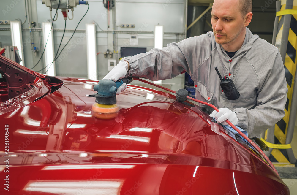 Fototapeta premium Employee in the shop painting the car body polishes painted body parts