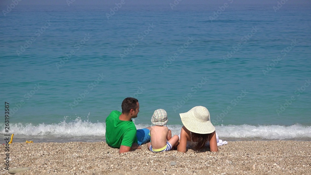 Family, young parents and little child resting on beach, turquoise sea waving Family, young parents and little child resting on beach, turquoise sea waving