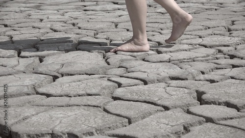 Feet walking on arid and cracked soil, bare fee going on dry ground, conceptual