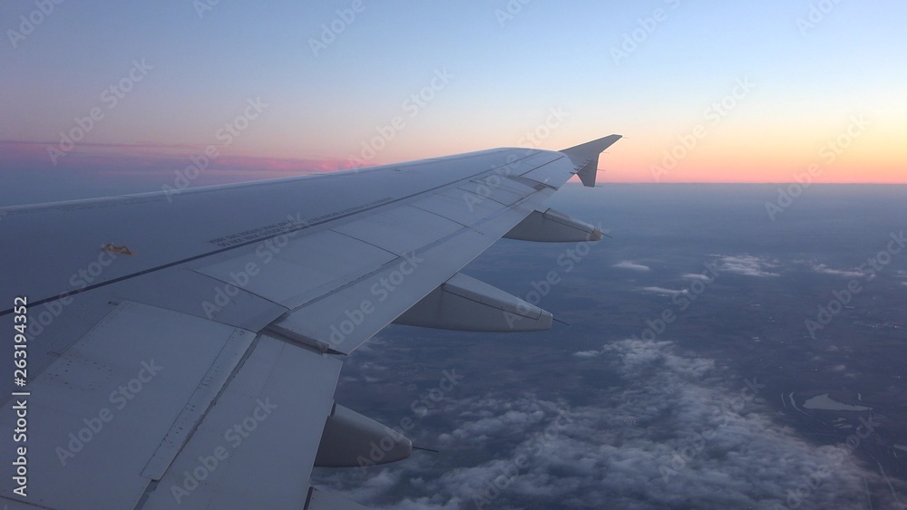 Airplane wing seen on window and sunset red sky