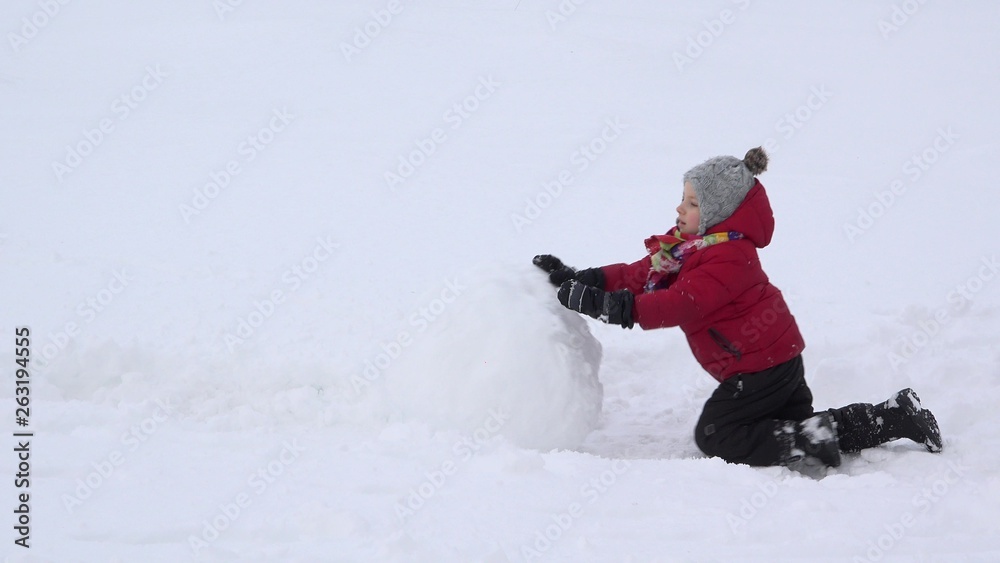 Little child pushing a big snowball, determined boy do his job, colorful life