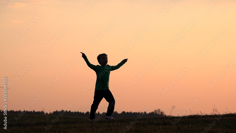 © MEDIAIMAG - Happy child silhouette playing, singing, dancing, moving hands close sunset colorful sky, symbol of joyful childhood, concept of freedom, gorgeous nature © MEDIAIMAG - Happy child silhouette playing, singing, dancing, moving hands close sunset colorful sky, symbol of joyful childhood, concept of freedom, gorgeous nature