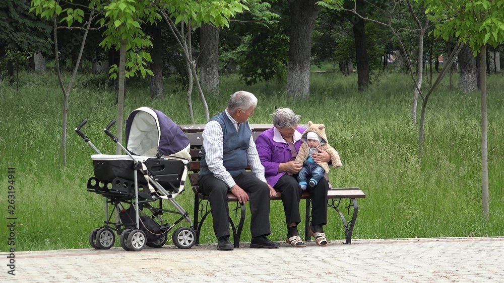 Grandparents with baby sitting on bench in the park, gray hair care Grandparents with baby sitting on bench in the park, gray hair care
