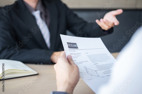 Employer or recruiter holding reading a resume during about colloquy his profile of candidate, employer in suit is conducting a job interview, manager resource employment and recruitment concept