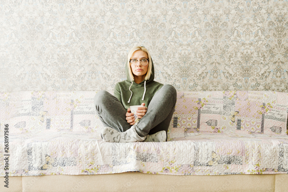 Fototapeta premium girl in a sweatshirt and glasses sitting on the couch