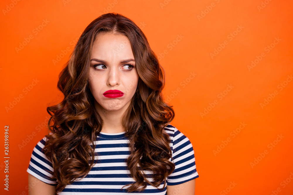 Close up photo beautiful she her lady red lipstick pomade look side empty  space not satisfied weather bad mood wear casual striped white blue t-shirt  clothes isolated orange bright background Stock Photo
