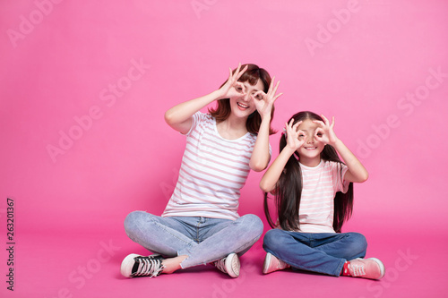 happy mother and daughter holding fingers near eyes