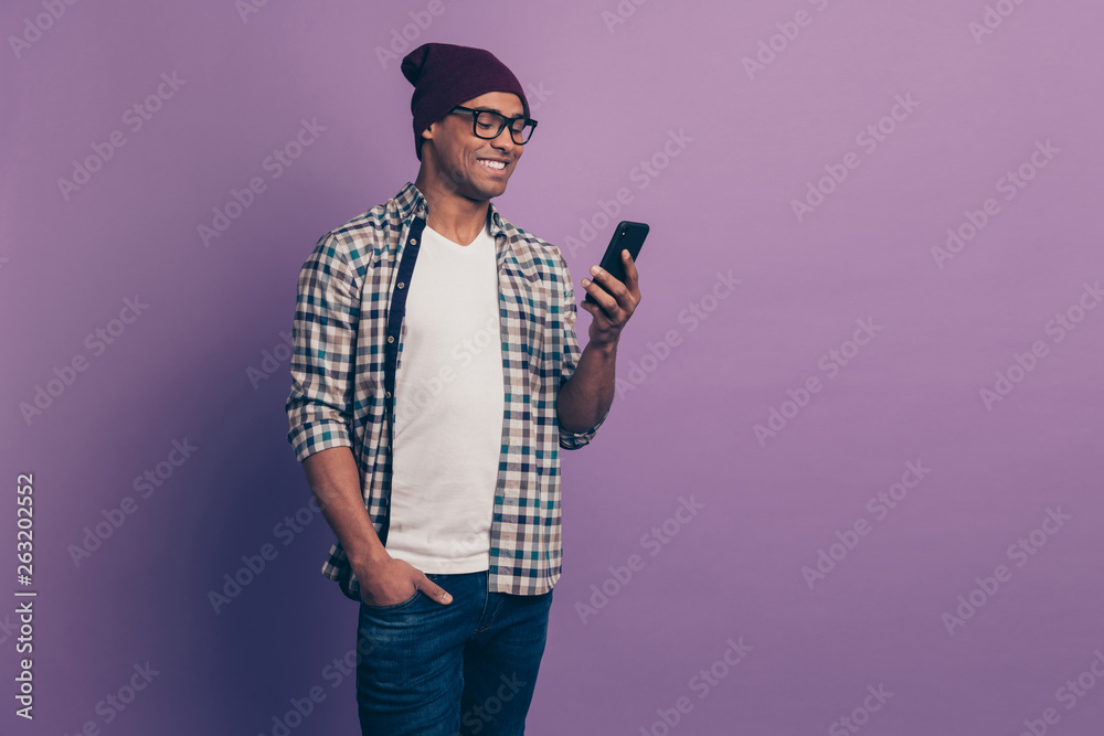 Portrait of cheerful positive millennial with beaming toothy smile using holding modern gadget device in hands putting palm in denim trousers isolated violet background Portrait of cheerful positive millennial with beaming toothy smile using holding modern gadget device in hands putting palm in denim trousers isolated violet background