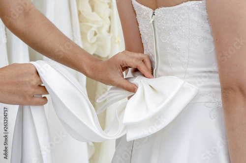 Wedding help. Hands of bridesmaid on bridal dress.