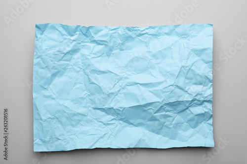 Color sheet of crumpled paper on grey background, top view