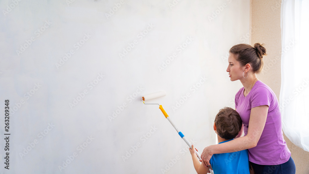 a child with his mother paint the walls. finishing work in the premises of the artist paints the walls. repair of premises, premises of the house. the child helps to paint the walls.copy space a child with his mother paint the walls. finishing work in the premises of the artist paints the walls. repair of premises, premises of the house. the child helps to paint the walls.copy space