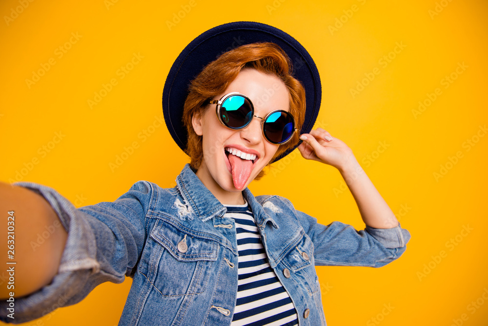 Close up photo funny funky foxy she her lady make take selfies  tongue out mouth naughty behavior wear specs vintage hat casual striped t-shirt jacket jeans denim isolated yellow bright background
