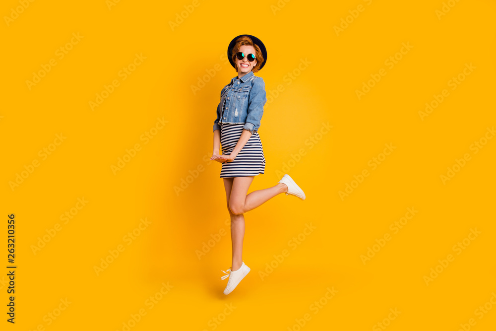Full length side profile body size photo foxy she her chic lady jumping high sunny day fine weather weekend wear specs vintage hat casual striped dress jeans denim isolated yellow bright background Full length side profile body size photo foxy she her chic lady jumping high sunny day fine weather weekend wear specs vintage hat casual striped dress jeans denim isolated yellow bright background