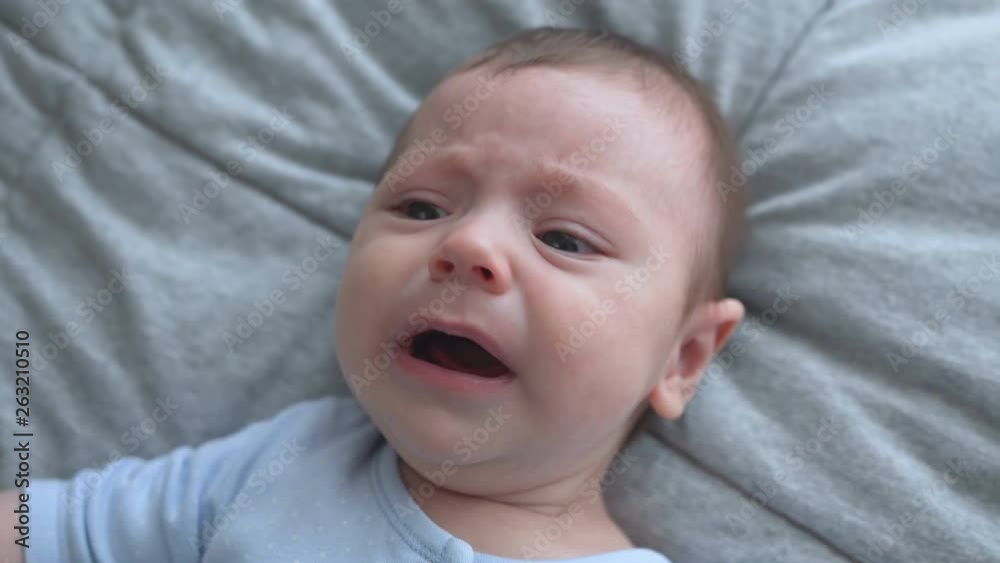 Close-up of crying newborn baby. Face close newborn lies, close-up, top view Close-up of crying newborn baby. Face close newborn lies, close-up, top view