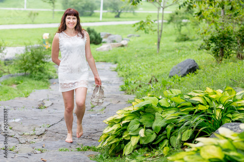 Portrait of cute young caucasian woman in nice white dress in the summer park.